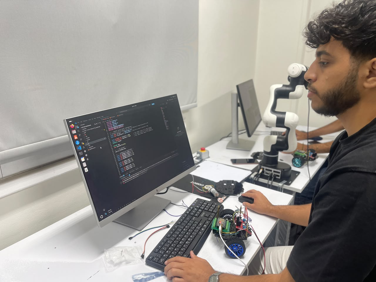 طالب يبرمج روبوت متنقل بجانب ذراع DOBOT